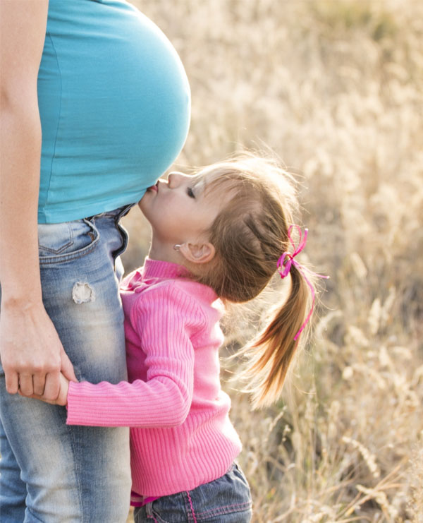 Child kissing her pregnant mother's belly