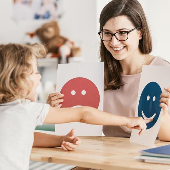 Child and teacher working with emotion cards during flexible in-person therapy