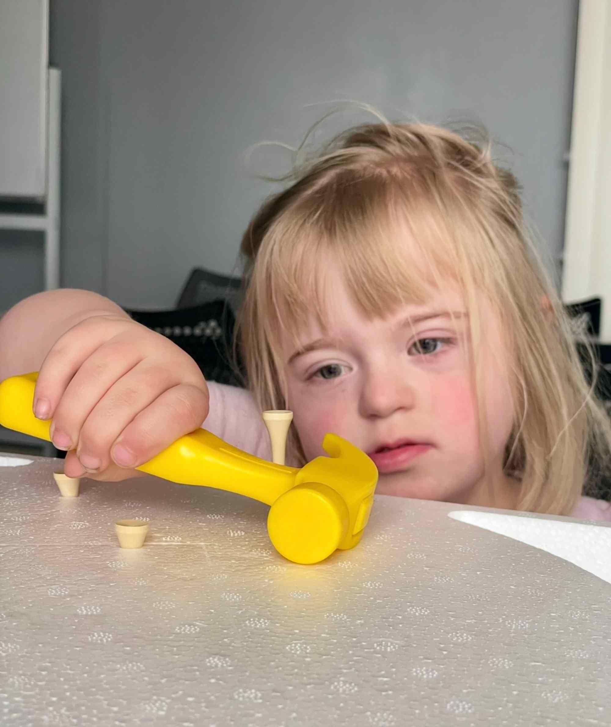 Young child playing with a yellow toy hammer in the infant development program (ages 0–5)