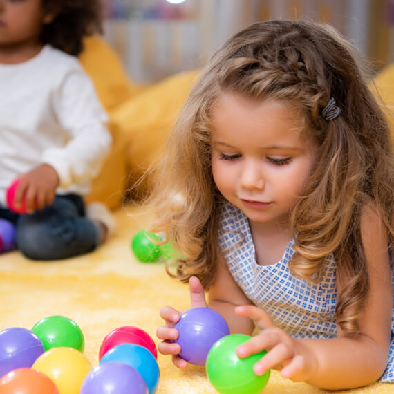 Toddler playing with colorful sensory balls during early intervention therapy