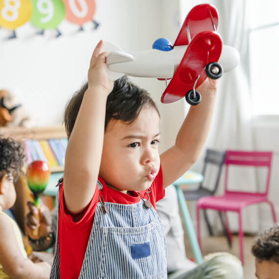 Boy holding a red and white toy airplane, building skills for a bright future
