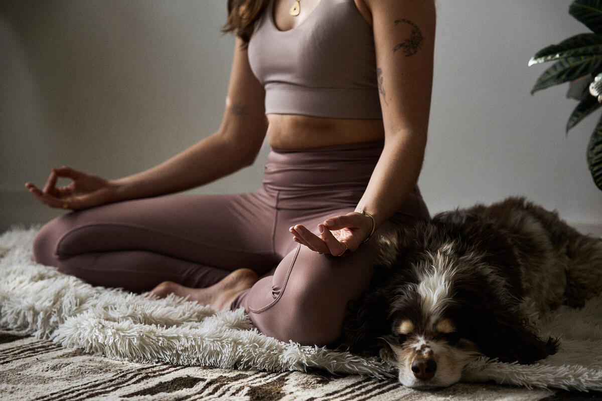 Femme en posture de méditation, assise près de son chien