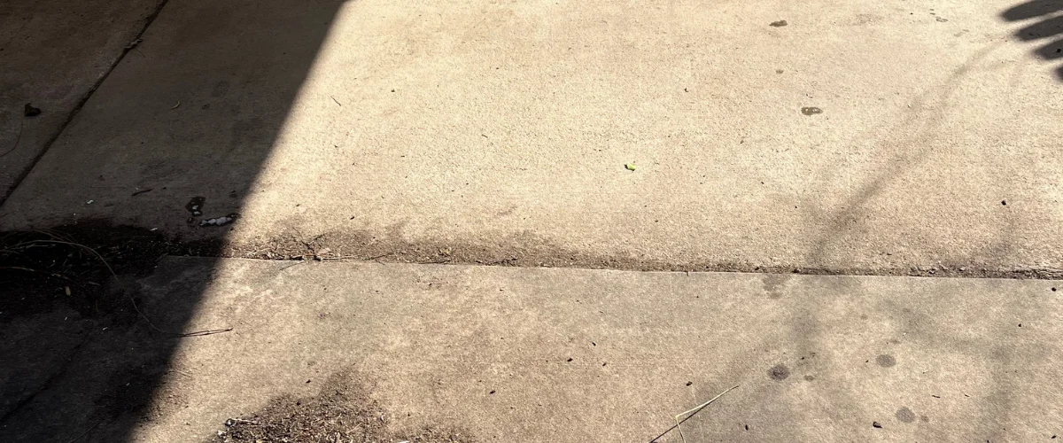 A concrete sidewalk with a diagonal shadow cutting across its surface on a sunny day.