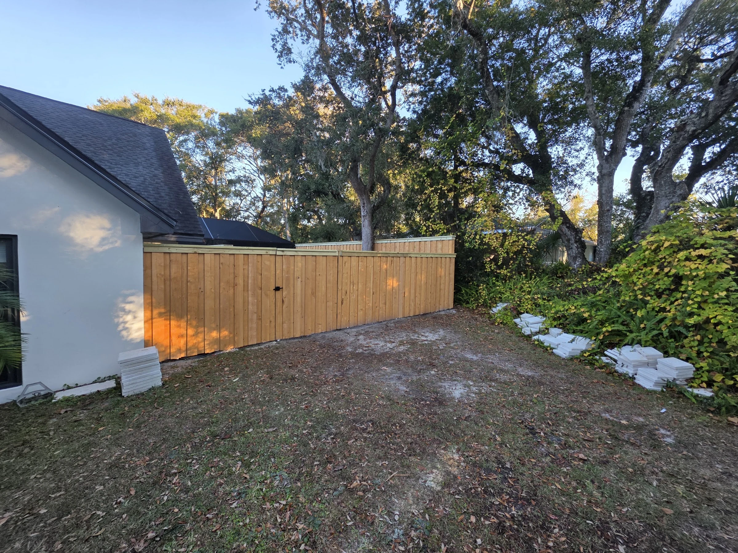 New wood privacy fence closing in a backyard under oak trees in St. Augustine, FL