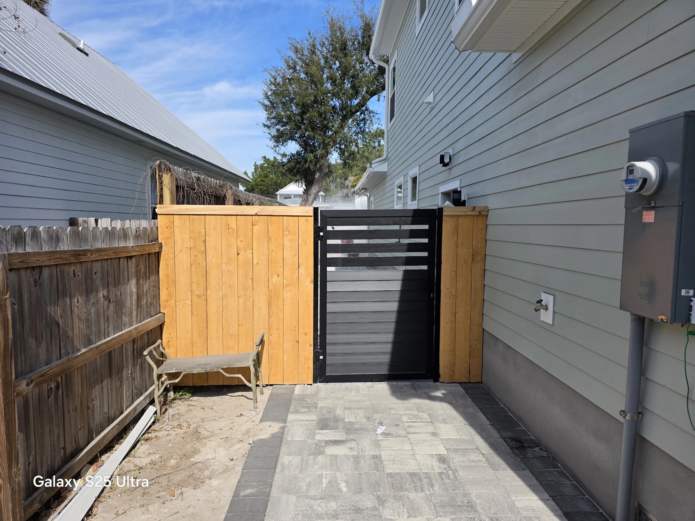 Wood privacy fence with a modern horizontal slat gate beside a home in St. Augustine, FL