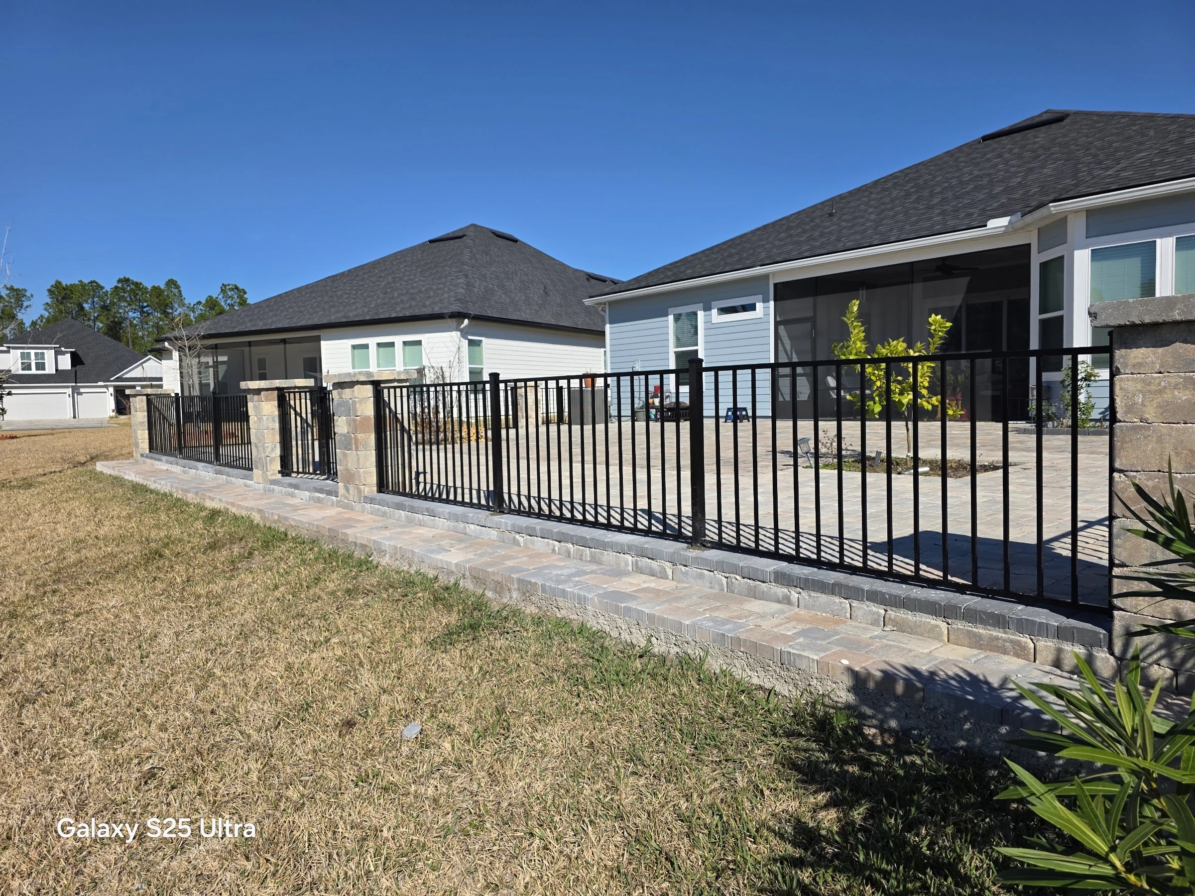 Black aluminum fence on a paver seat wall around a backyard in St. Augustine, FL