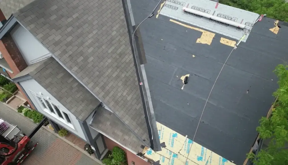 Aerial view of residential roof with exposed underlayment and visible damage before repair work begins