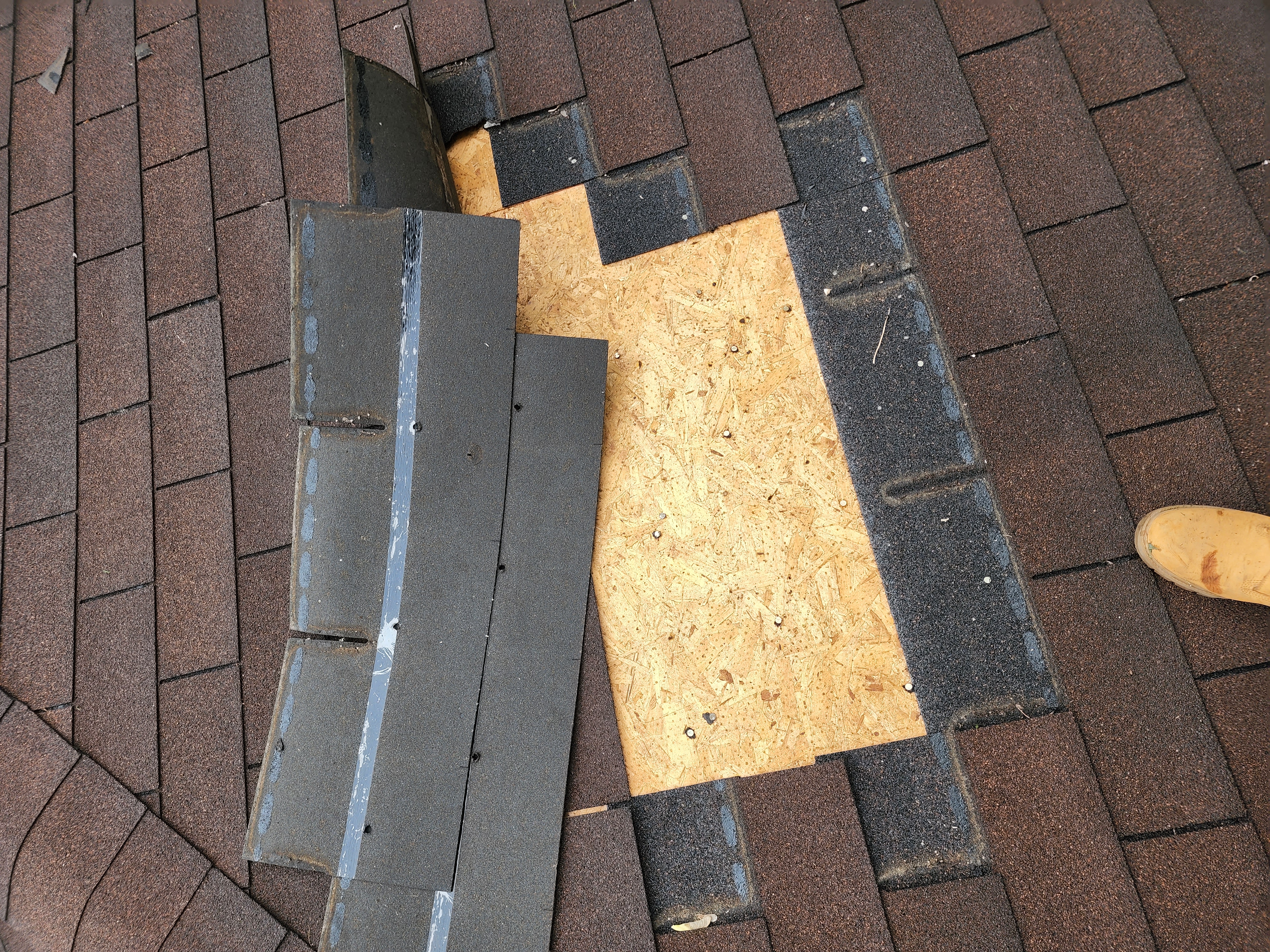 Brick home with worn and missing roof shingles showing visible damage before residential roof repair work begins