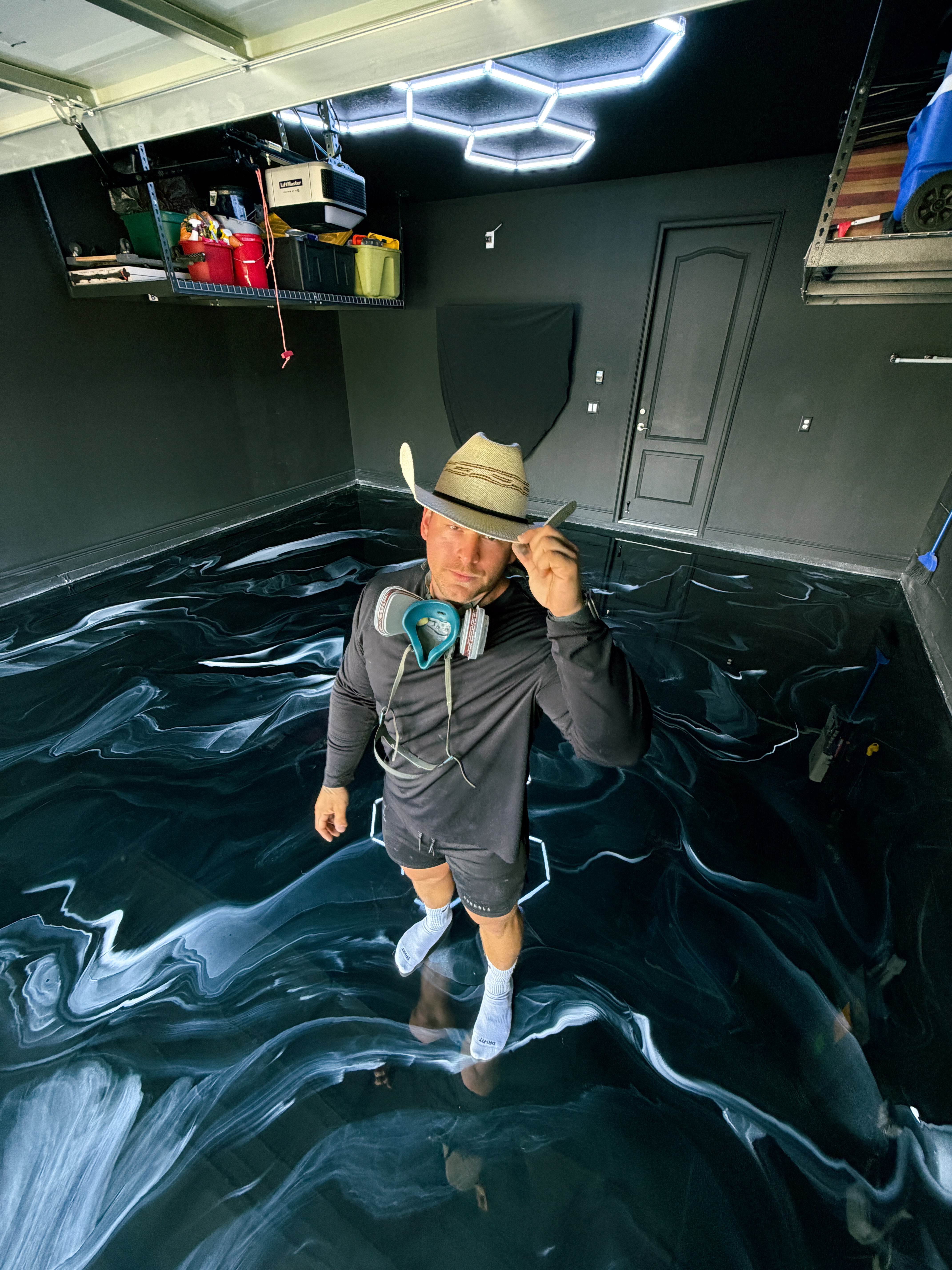 Contractor standing on black and white metallic epoxy garage floor in Tampa Florida with high gloss finish and custom swirl design