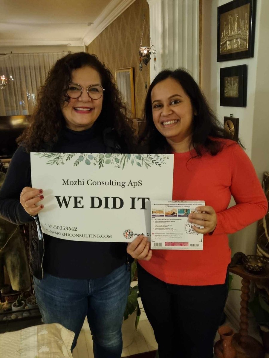 Mozhgan celebrating a new job with a client, holding a "We did it" sign