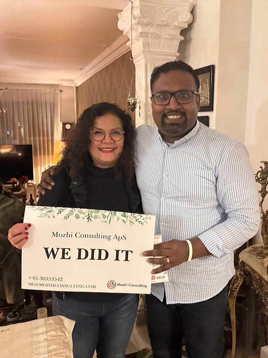 Mozhgan celebrating a new job with a client, holding a "We did it" sign