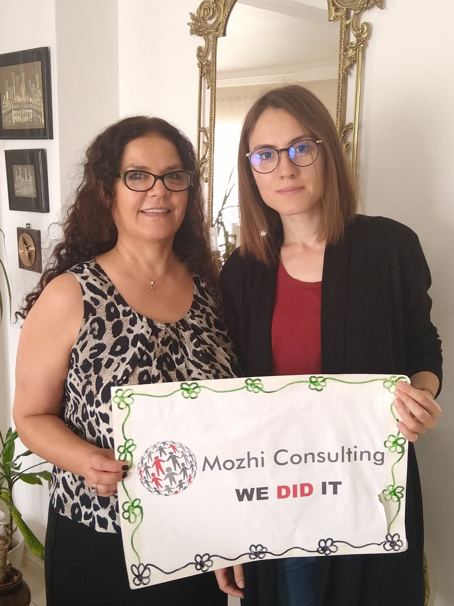 Mozhgan celebrating a new job with a client, holding a "We did it" sign