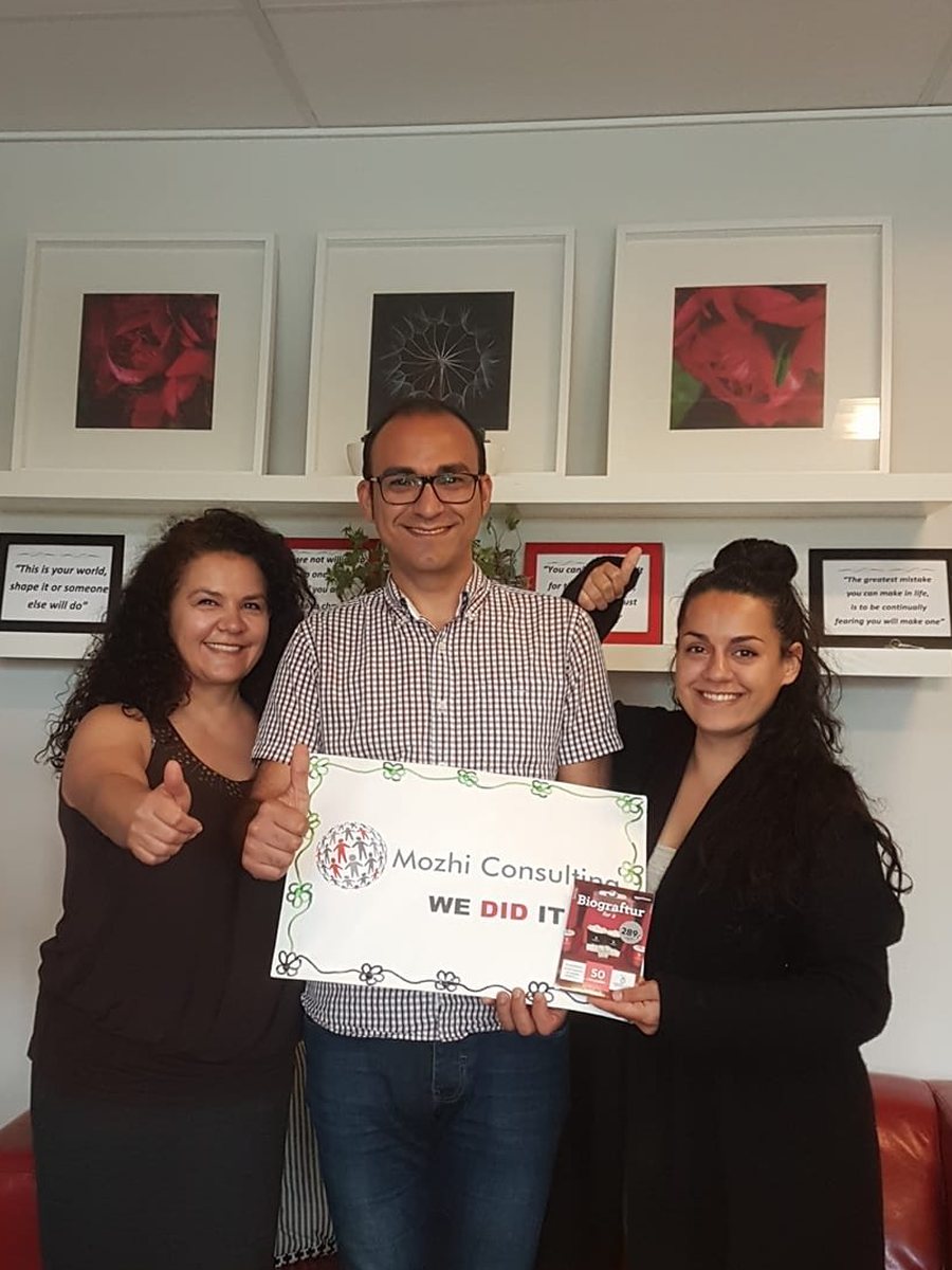 Mozhgan celebrating a new job with a client, holding a "We did it" sign