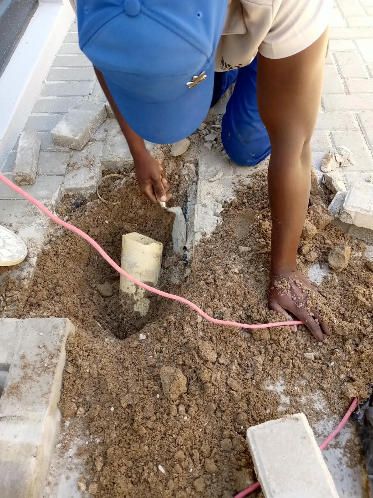 Mis-tic crew installing a pipe in the ground beside block paving