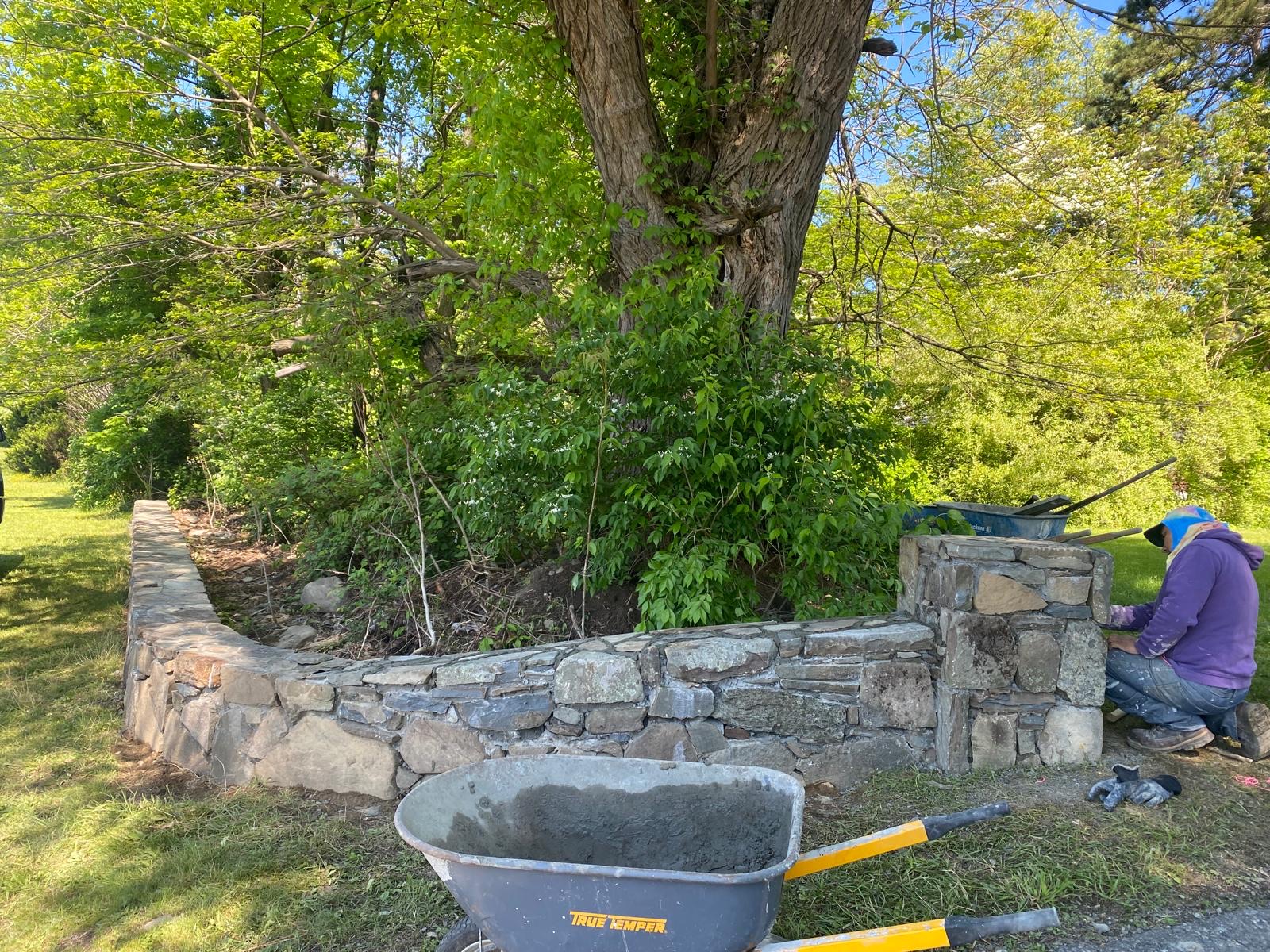 Crew member building a natural stone wall on site