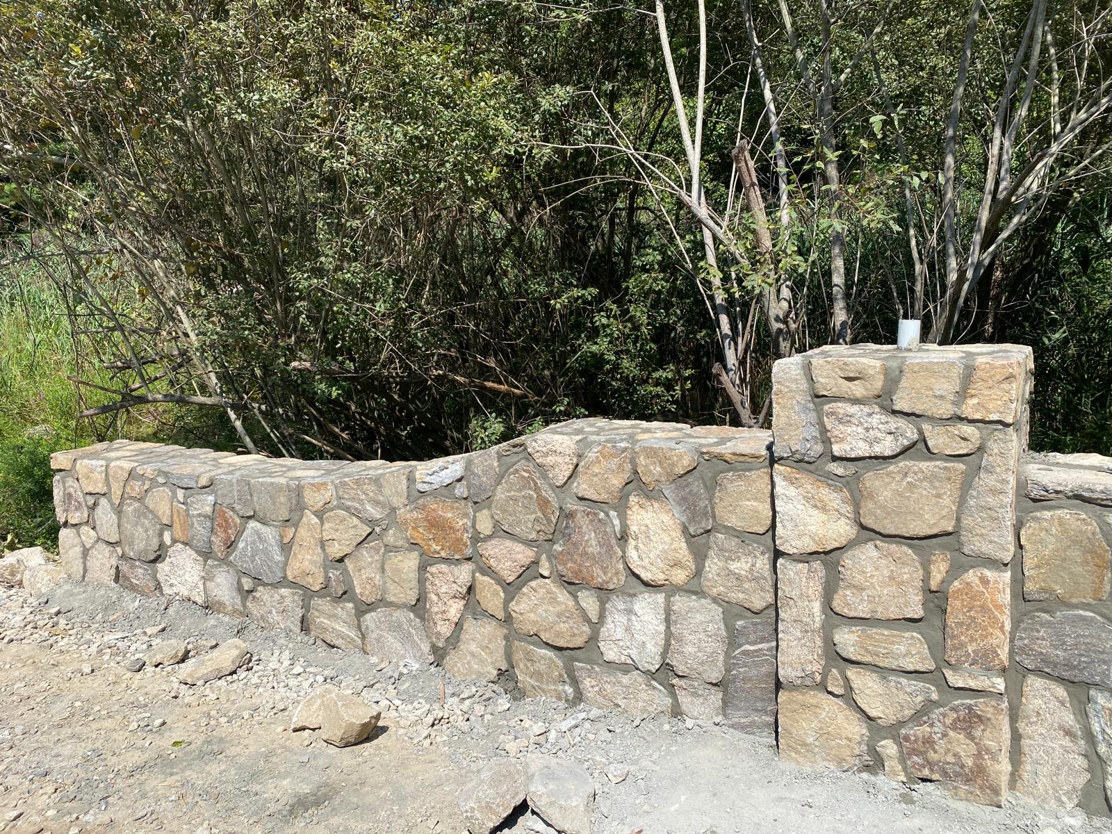 Stone pillar wall with a capstone in a landscaped yard