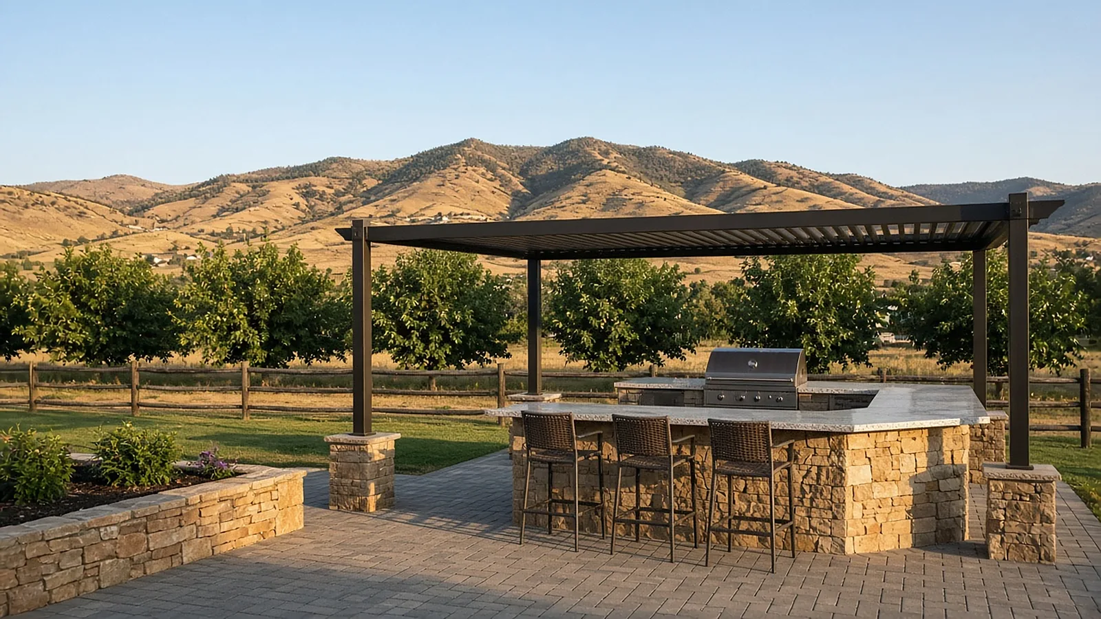 Outdoor kitchen with stone BBQ island and pergola in Emmett, Idaho, with foothills beyond the backyard