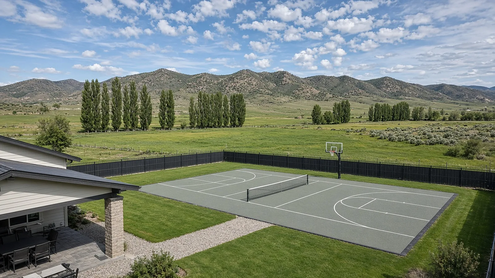 Wide view of a multi-use backyard sport court with pickleball lines and basketball hoop on acreage in Emmett, Idaho
