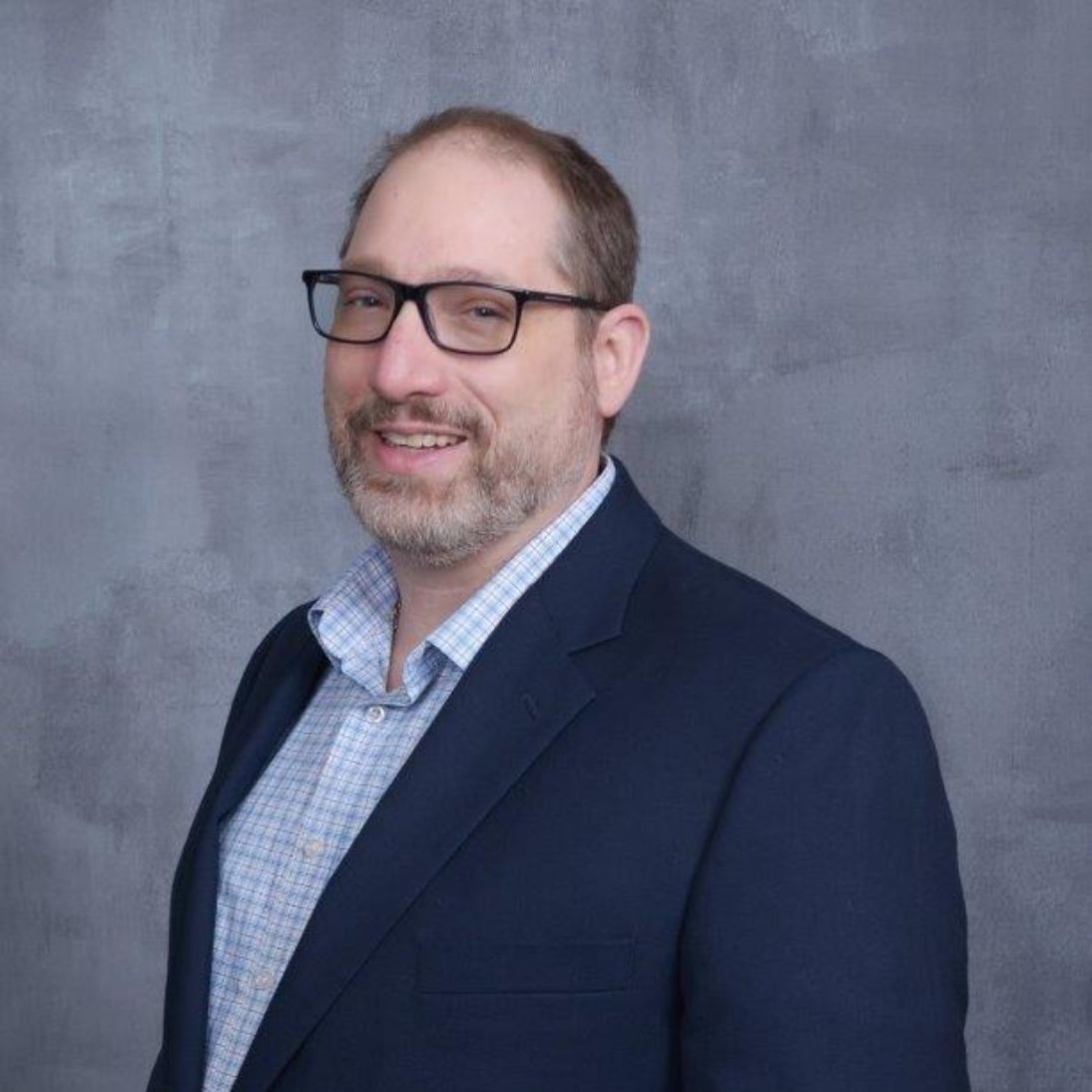 Group of HR and M&A leaders collaborating around a laptop, discussing strategies to drive successful cultural integration in mergers.