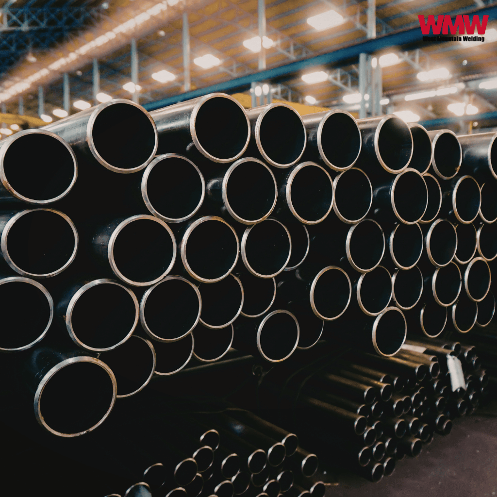 Stacked black carbon steel pipes in a bright industrial warehouse setting Stacked black carbon steel pipes in a bright industrial warehouse setting