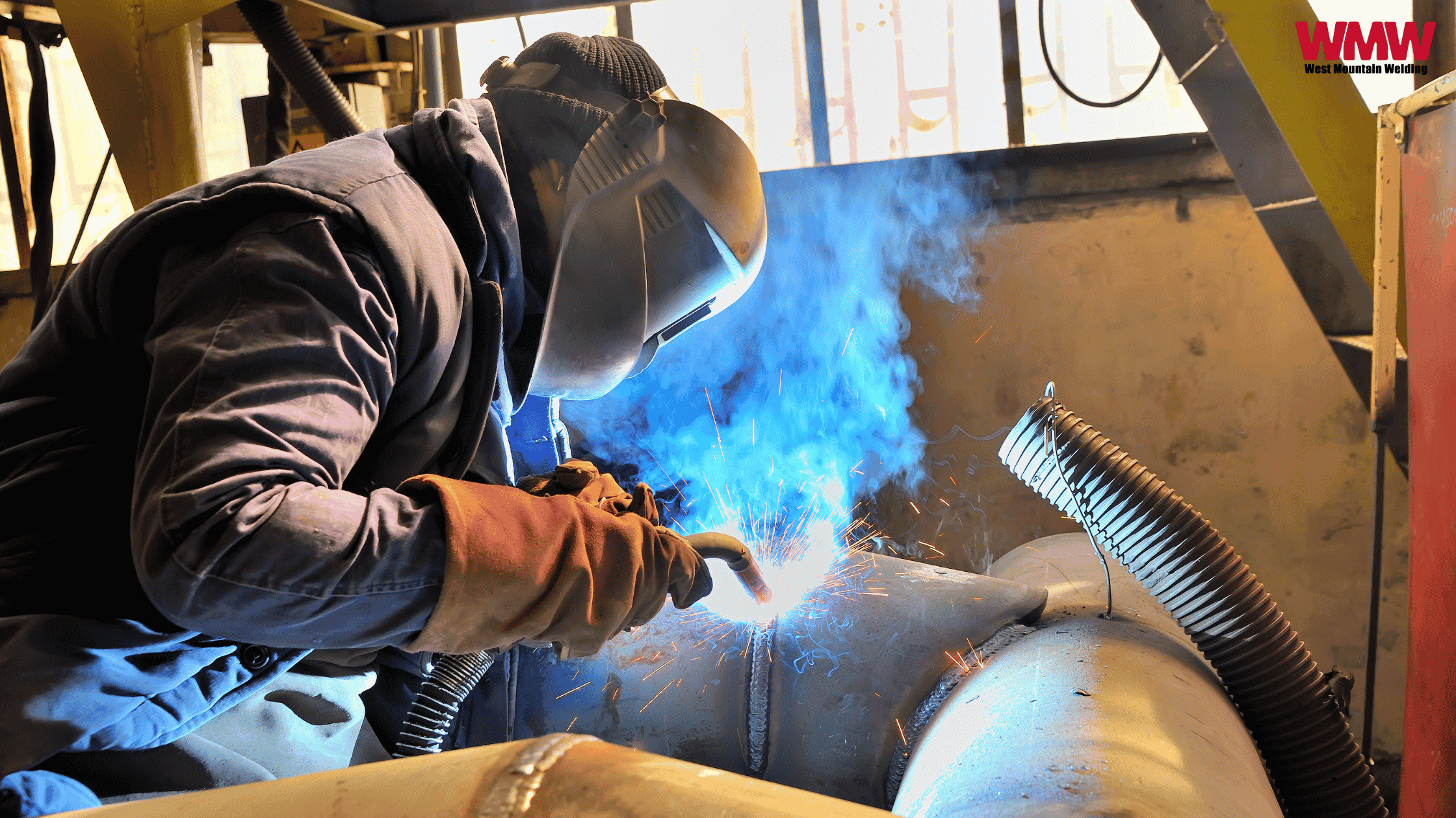 A welder in action, surrounded by blue smoke rising from his helmet, showcasing the welding process and safety gear. A welder in action, surrounded by blue smoke rising from his helmet, showcasing the welding process and safety gear.