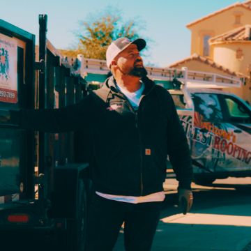 A Mesa roofing specialist from Arizona’s Finest Roofing inspecting a residential property with a service truck and trailer on-site.