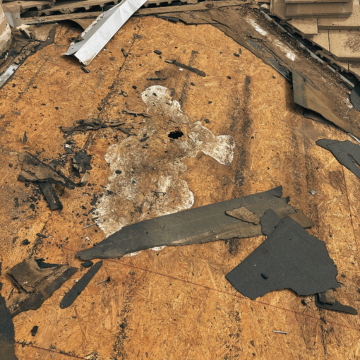 Damaged wooden roof decking and torn underlayment being inspected by a residential roofer in Scottsdale AZ during a re-roofing Scottsdale AZ project.
