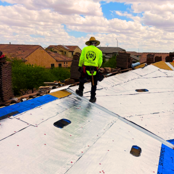 A professional roofing contractor installing high-quality radiant barrier underlayment on a residential home in Phoenix, Arizona, to improve energy efficiency against the desert heat.
