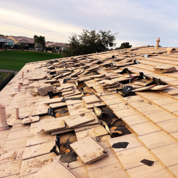 Extensive wind damage to a residential roof requiring professional roof repair Apache Junction, showing displaced and broken concrete tiles.