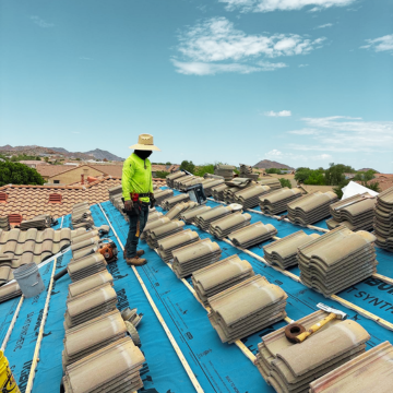 A roofer preparing for tile installation with stacks of tiles, showcasing the best emergency tile roof services mesa az.