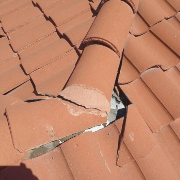 Broken clay tile exposing the underlayment on a residential roof, illustrating a common roof leaking queen creek az issue that needs immediate attention.