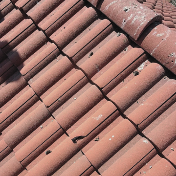 Close-up view of weathered terracotta tiles requiring emergency roofing chandler az to fix cracks and debris.