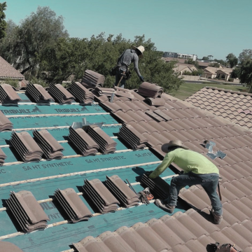 Professional tile roofers chandler az installing new synthetic roof underlayment chandler az and stacking terracotta tiles on a residential home.