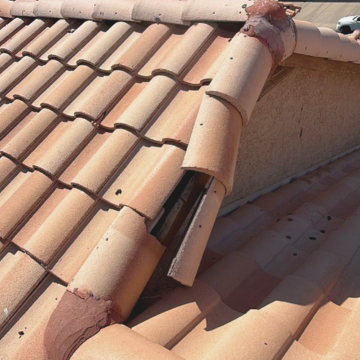 Close-up of damaged and cracked Spanish clay roof tiles on a residential home requiring professional residential roof repair in scottsdale az. Close-up of damaged and cracked Spanish clay roof tiles on a residential home requiring professional residential roof repair in scottsdale az.