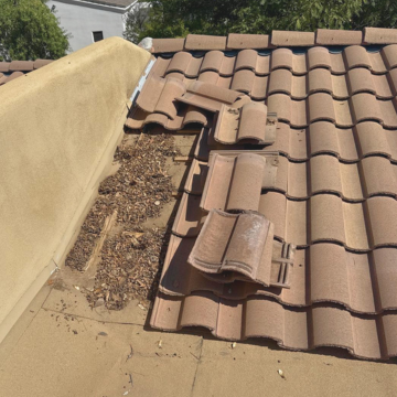 A section of a clay tile roof with several tiles removed, exposing dirt and debris underneath, highlighting the need for routine roof maintenance Scottsdale. A section of a clay tile roof with several tiles removed, exposing dirt and debris underneath, highlighting the need for routine roof maintenance Scottsdale.
