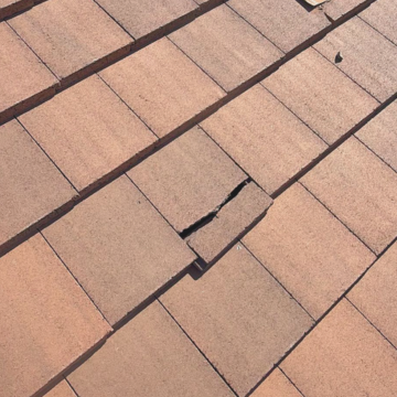 A close-up shot of a cracked concrete roof tile in need of professional repair. Call for a tile roofing estimate phoenix az to fix broken tiles. A close-up shot of a cracked concrete roof tile in need of professional repair. Call for a tile roofing estimate phoenix az to fix broken tiles.