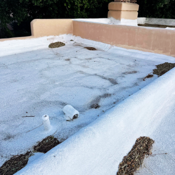 Flat roof displaying dirt accumulation and small debris along the parapet wall, requiring roof maintenance Scottsdale AZ.