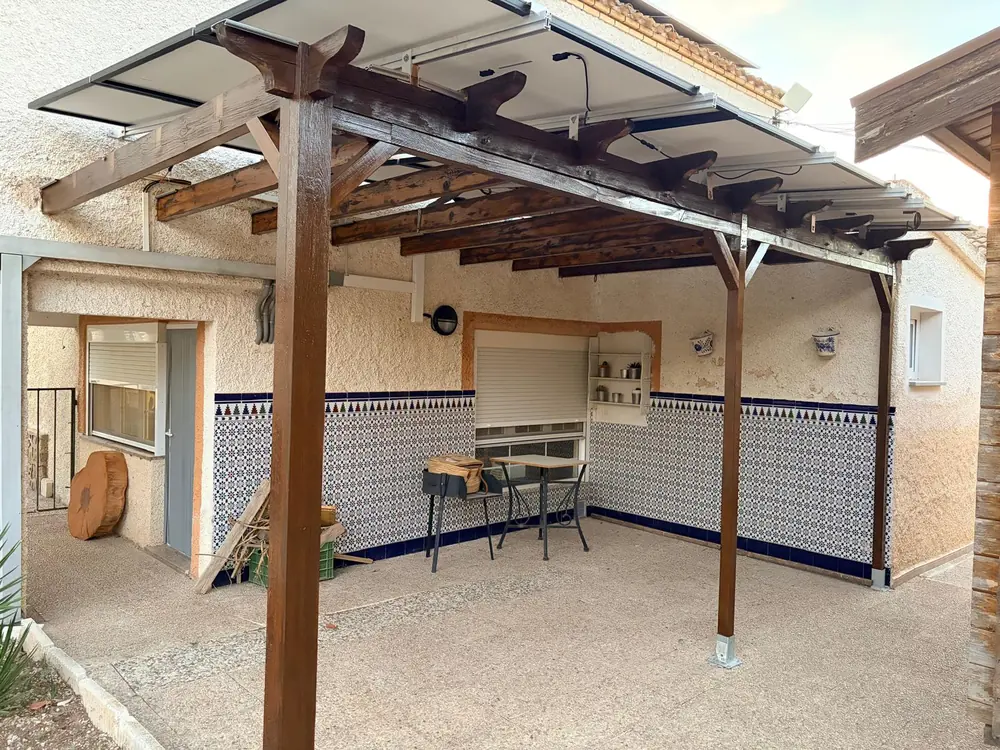 Pérgola de madera con placas solares sobre un patio de azulejos, vista desde abajo