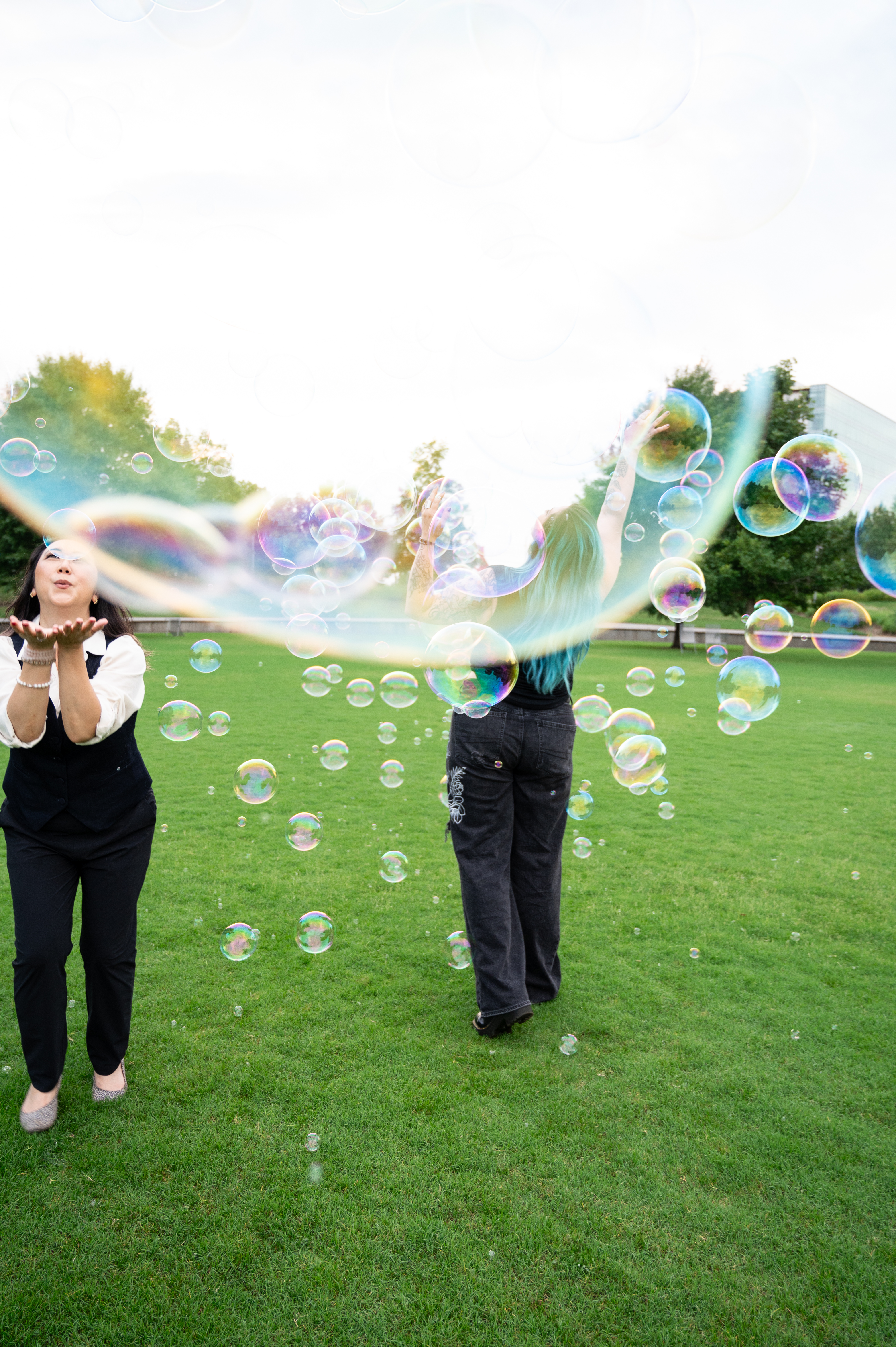 Two women laughing and blowing bubbles together outdoors