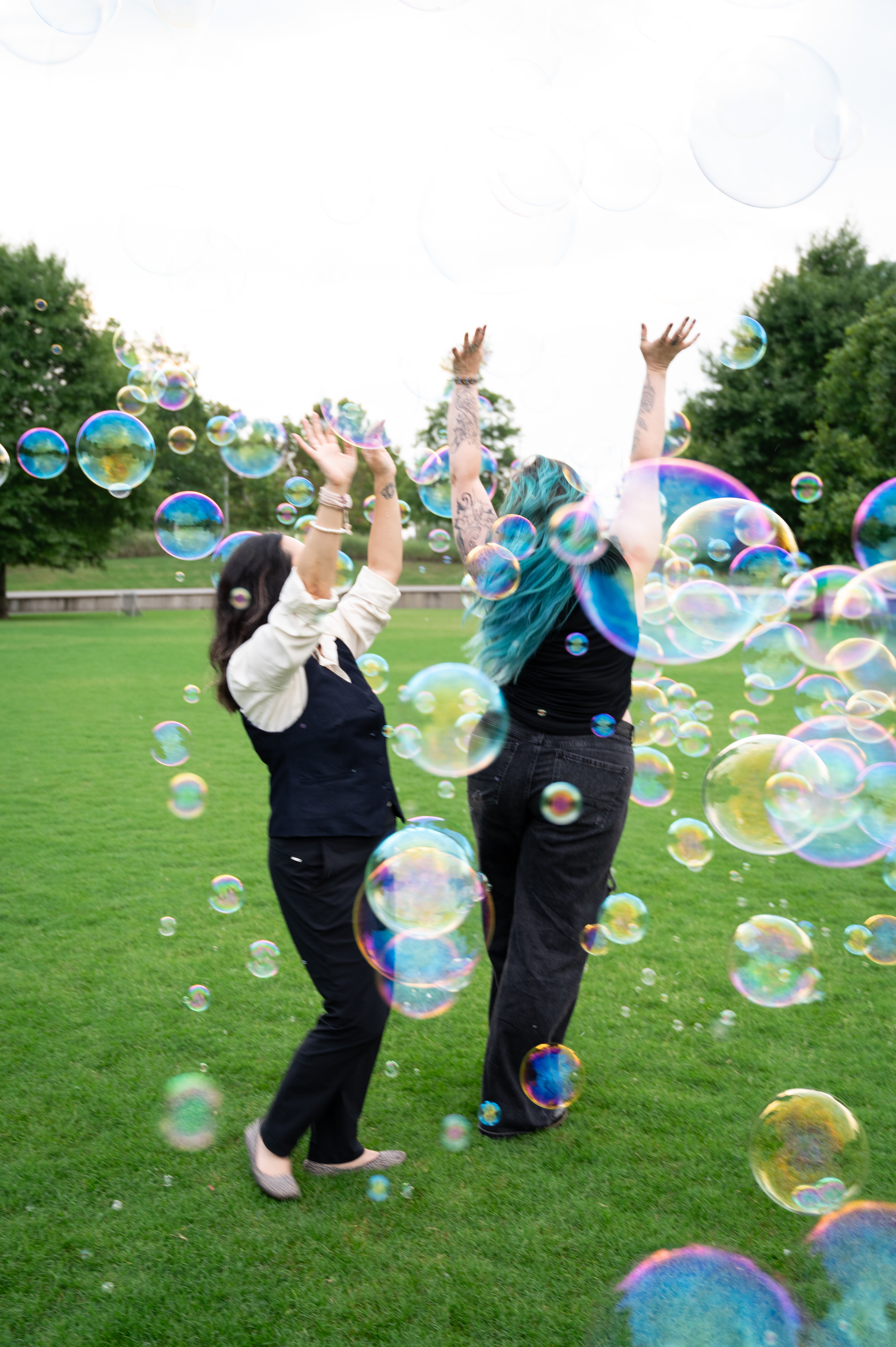 Two women playing together among bubbles in a park