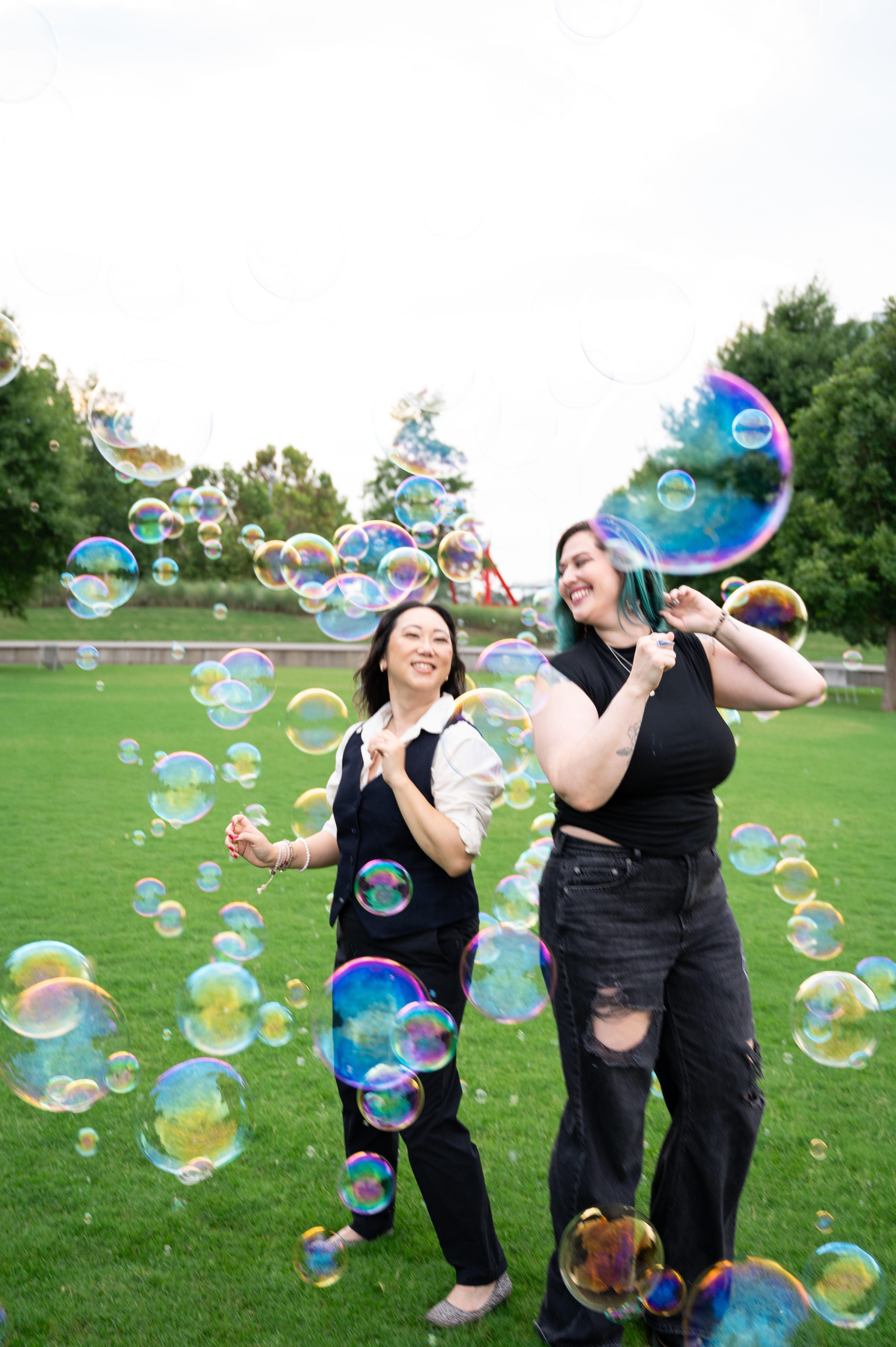 Sora and Kassy Hughes laughing together outdoors in a swirl of bubbles