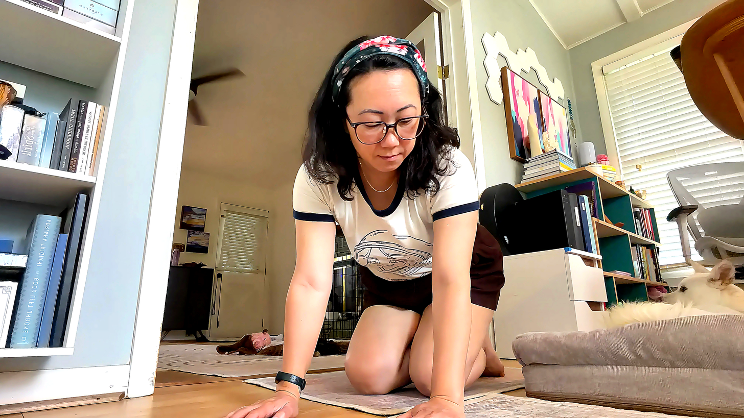 Sora Schilling kneeling on the floor of her room, hands flat in front of her, mirroring the five of cups card Sora Schilling kneeling on the floor of her room, hands flat in front of her, mirroring the five of cups card