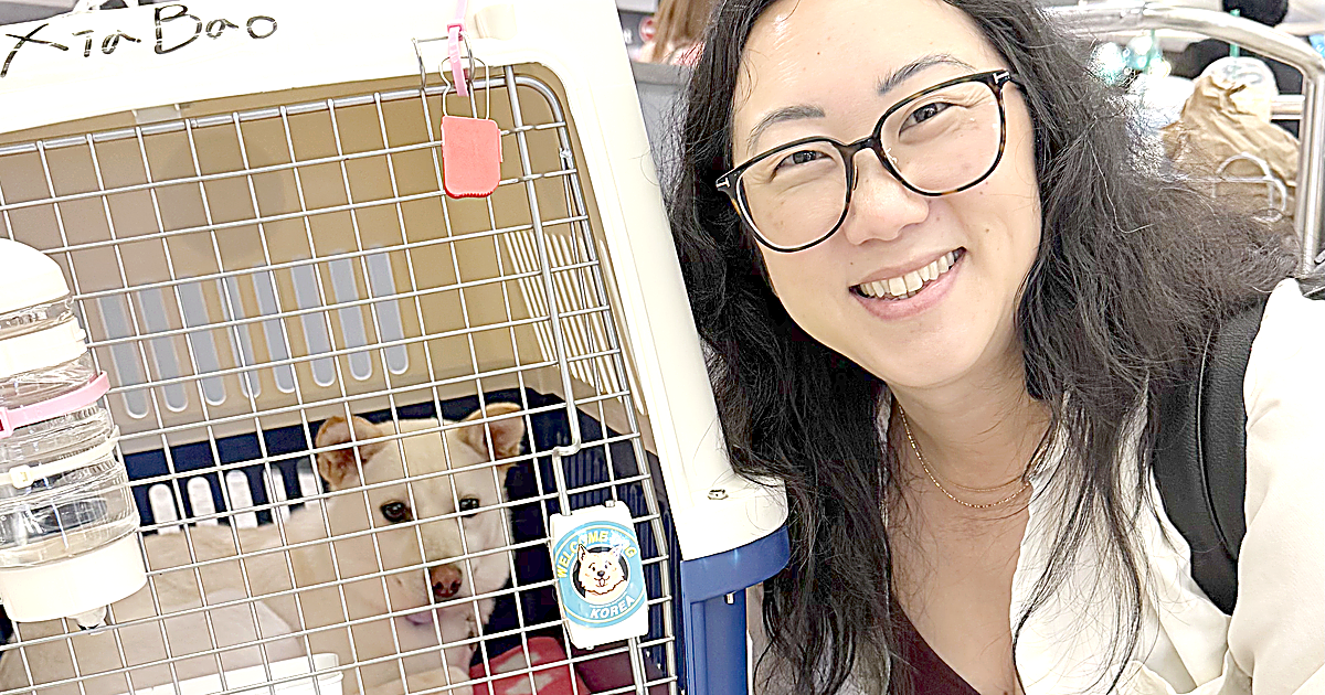 Sora Schilling smiling beside the travel crate with Xia Bao's name written on the side