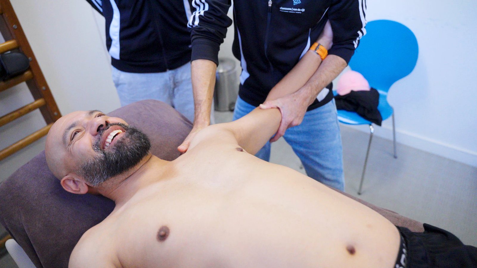 Hands-on behandeling van de schouder, de patiënt lacht