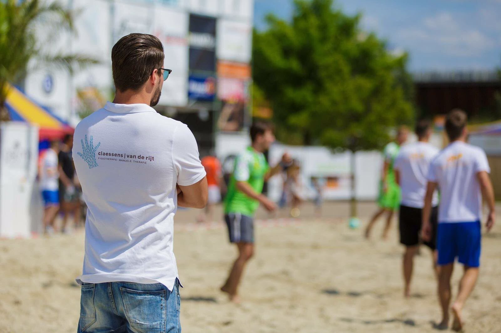 Collega in praktijkshirt bij een beachsporttoernooi