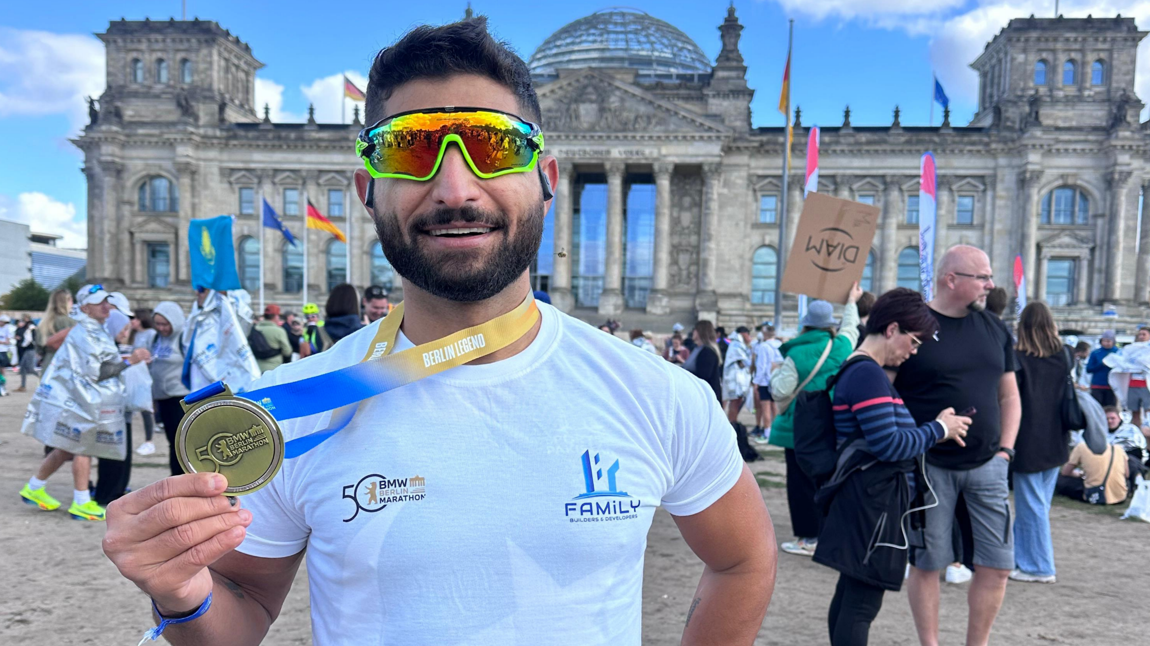 Shah Faisal Khan holding his Berlin Marathon medal in front of the Reichstag