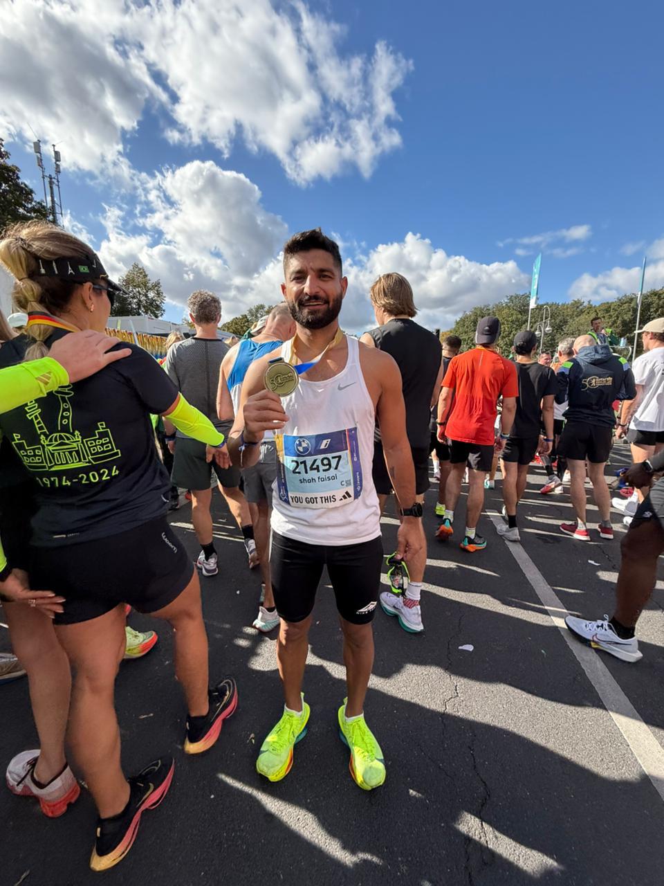 Shah Faisal Khan in a post-race crowd holding a marathon medal