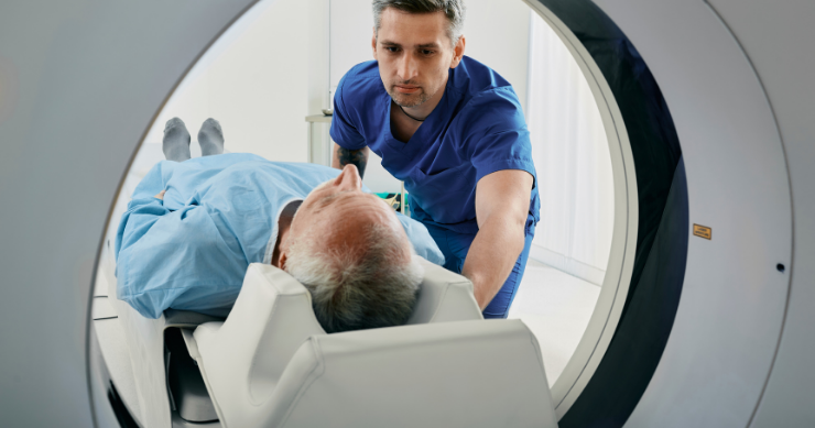 Un técnico en radiología preparando a un paciente mayor para un escáner de resonancia magnética (MRI). Un técnico en radiología preparando a un paciente mayor para un escáner de resonancia magnética (MRI).