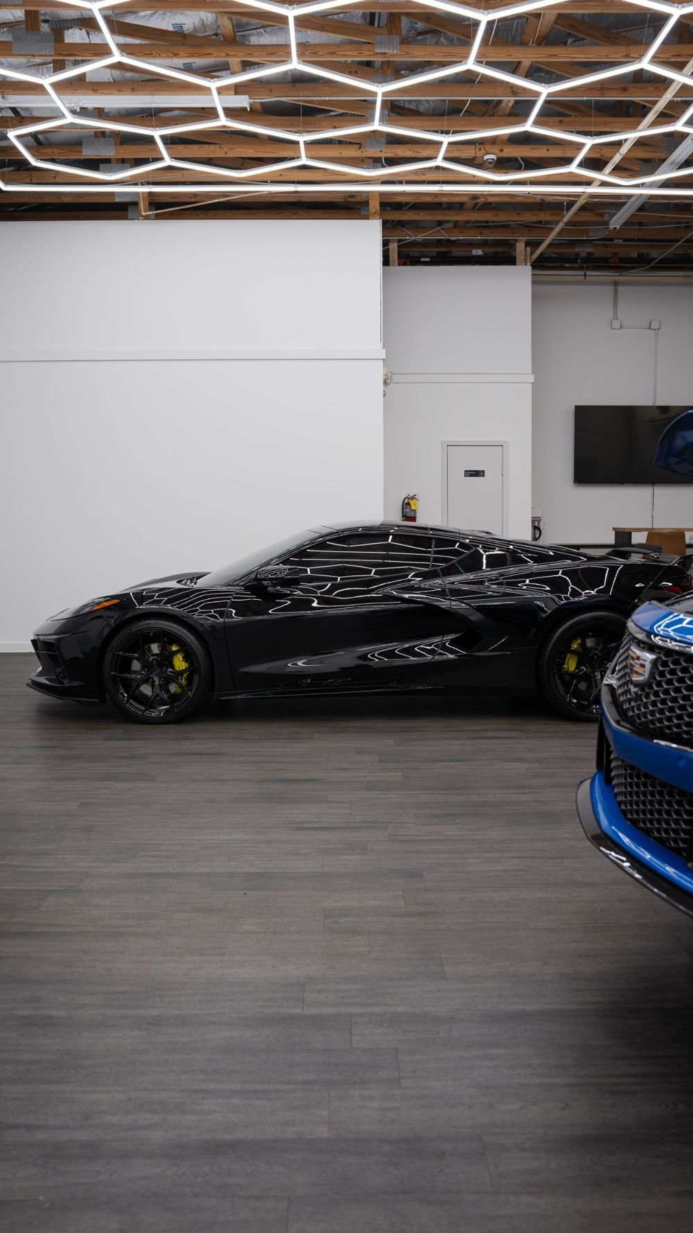 Glossy black Corvette C8 reflecting hexagon lights