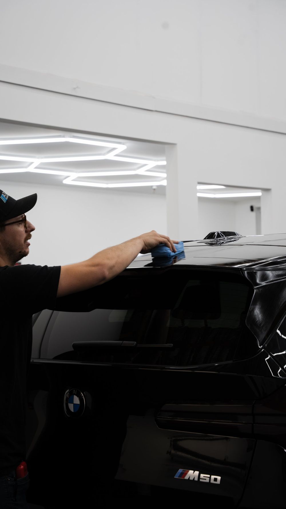 Technician applying ceramic coating to a black BMW X3 M50